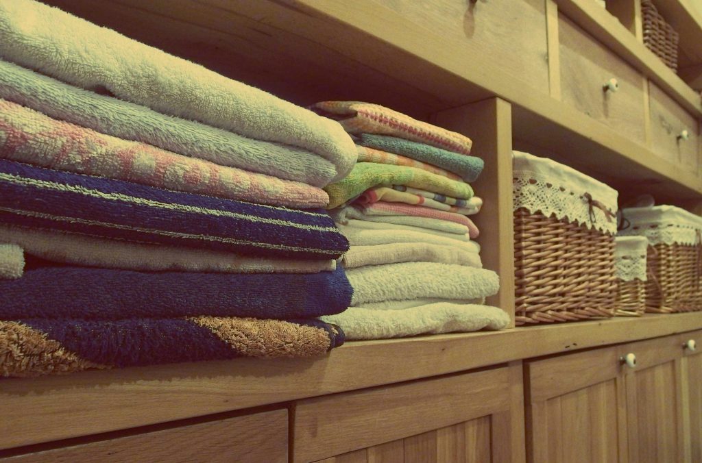 Tidy wooden cabinet with neatly stacked towels and decorative baskets in an indoor setting.