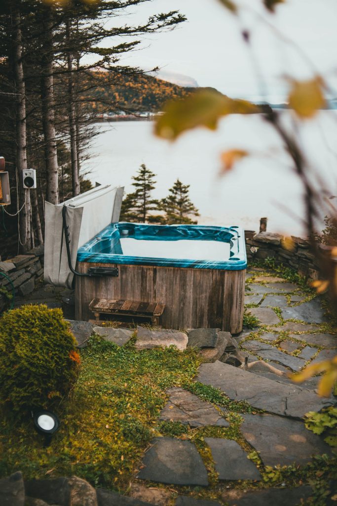 Serene outdoor hot tub with scenic lake view in autumn forest setting.