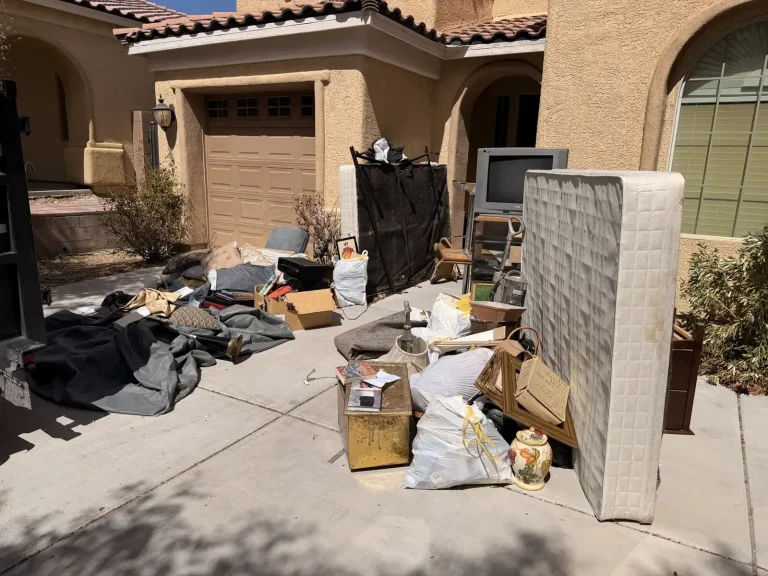 Household items including a mattress, box spring, TV and bags of belongings in a Centennial Hills driveway before junk removal